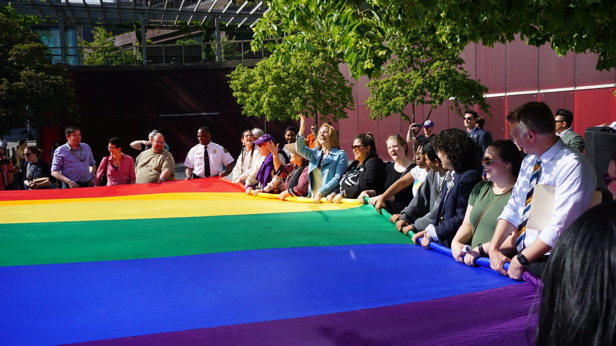 A group of people hold a large rainbow flag at a Seattle Pride event.