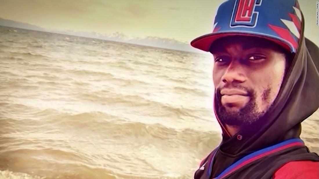 An image of Tyre Nichols at the beach. He is wearing a blue and red baseball cap with a blue and red sweatshirt.