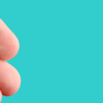 A hand holding a small, round, white pill.