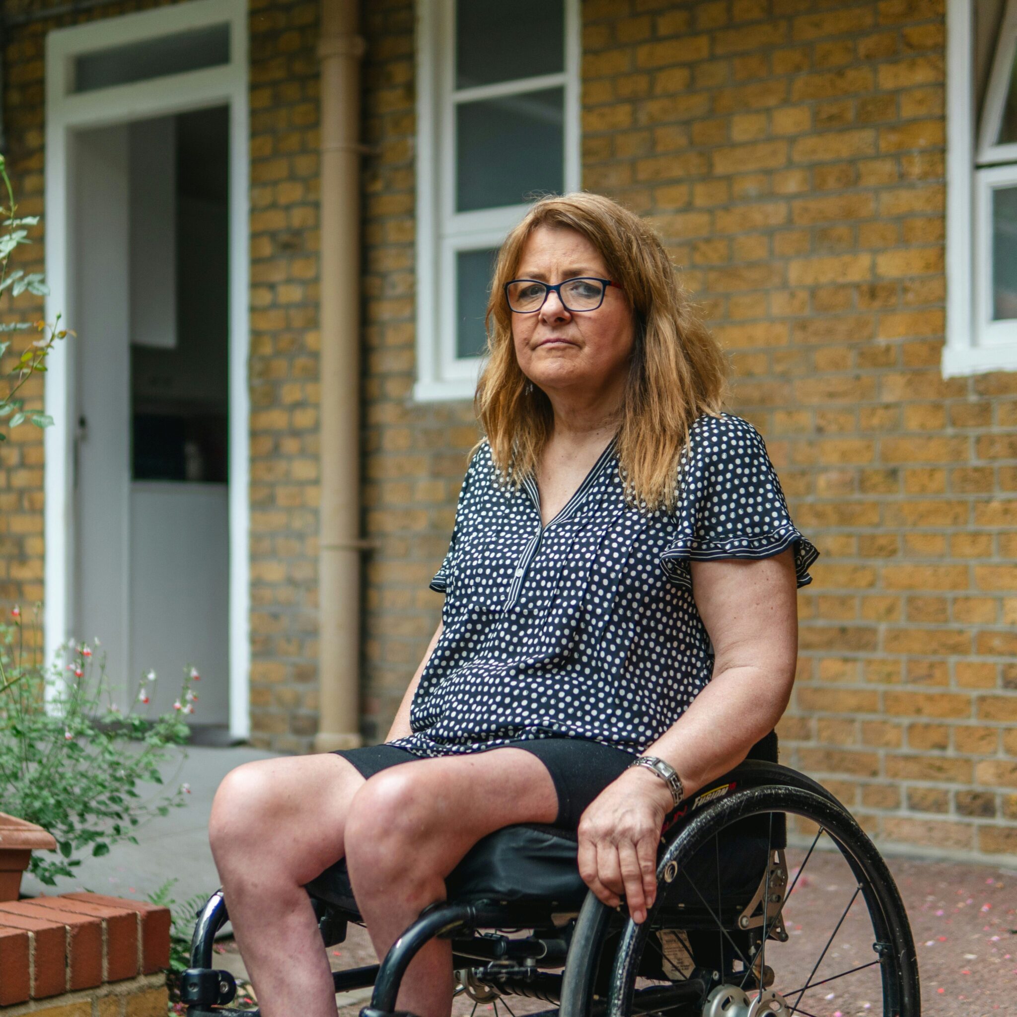 A woman in a wheelchair outside her home.
