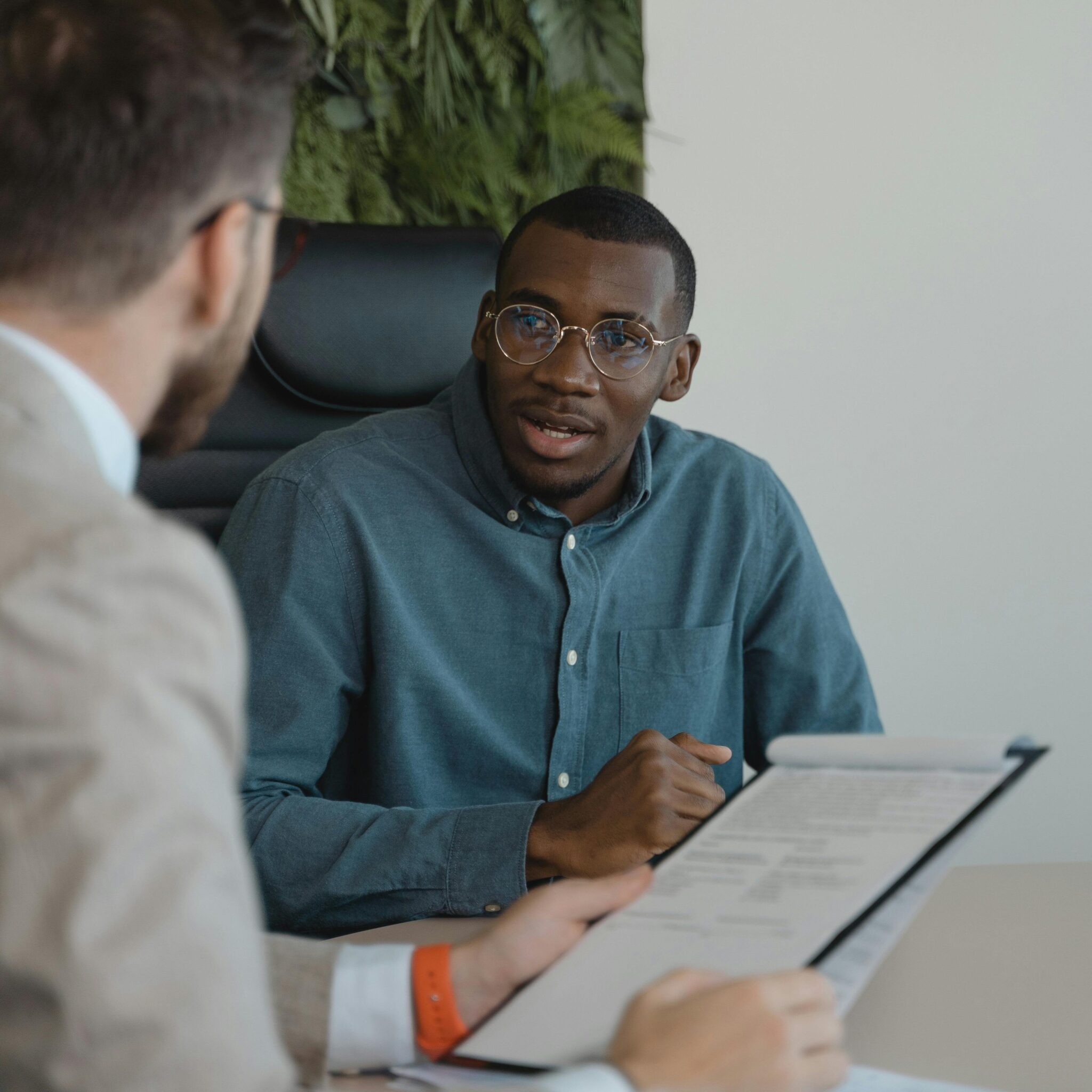 A Black employee in an office setting speaking with a white colleague.